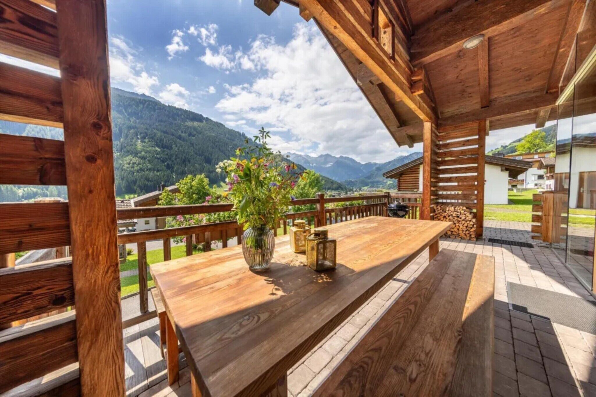 A wooden deck with a table and benches, overlooking a mountainous landscape.