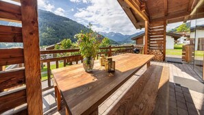 A wooden deck with a table and benches, overlooking a mountainous landscape.