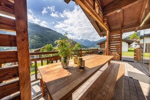 Une terrasse en bois avec une table et des bancs, offrant une vue sur un paysage montagneux.