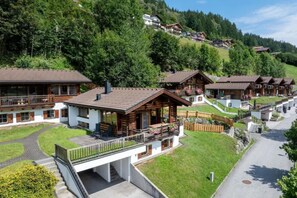 Een rij chalets met balkons, gelegen in een bergachtig gebied met heldere lucht.