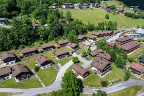 Vue aérienne d’un quartier résidentiel avec de nombreuses maisons à deux étages, des routes et des espaces verts.