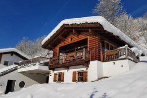 Een houten chalet met een balkon, omringd door met sneeuw bedekte bomen.