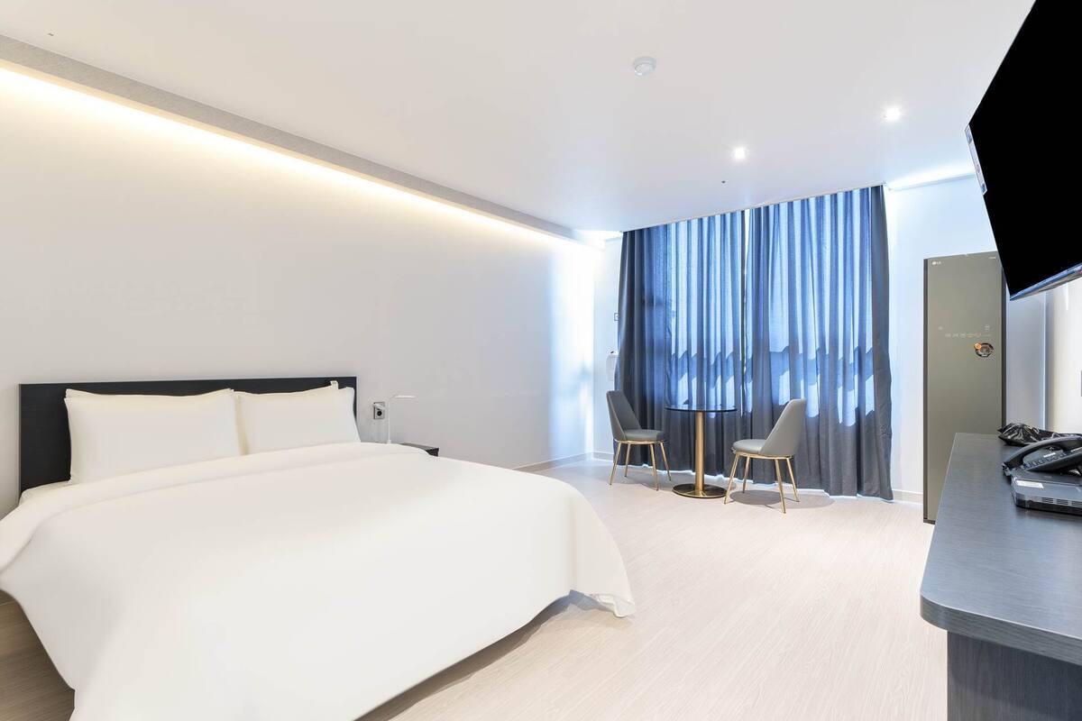 Une chambre d’hôtel moderne avec un grand lit, un bureau avec un téléphone et une chaise.
