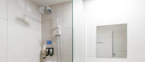 A modern bathroom with a glass shower enclosure, a white sink, and a mirror.