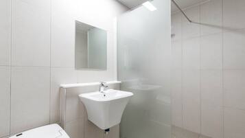 A modern bathroom with a white sink, a mirror, and a glass shower enclosure.