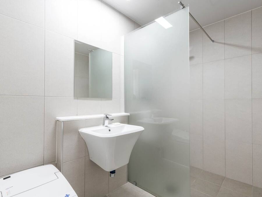 A modern bathroom with a white sink, a mirror, and a glass shower enclosure.