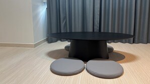 A round table with two grey cushioned seats in front. - HOTEL DEOKYEONG (Wonju)