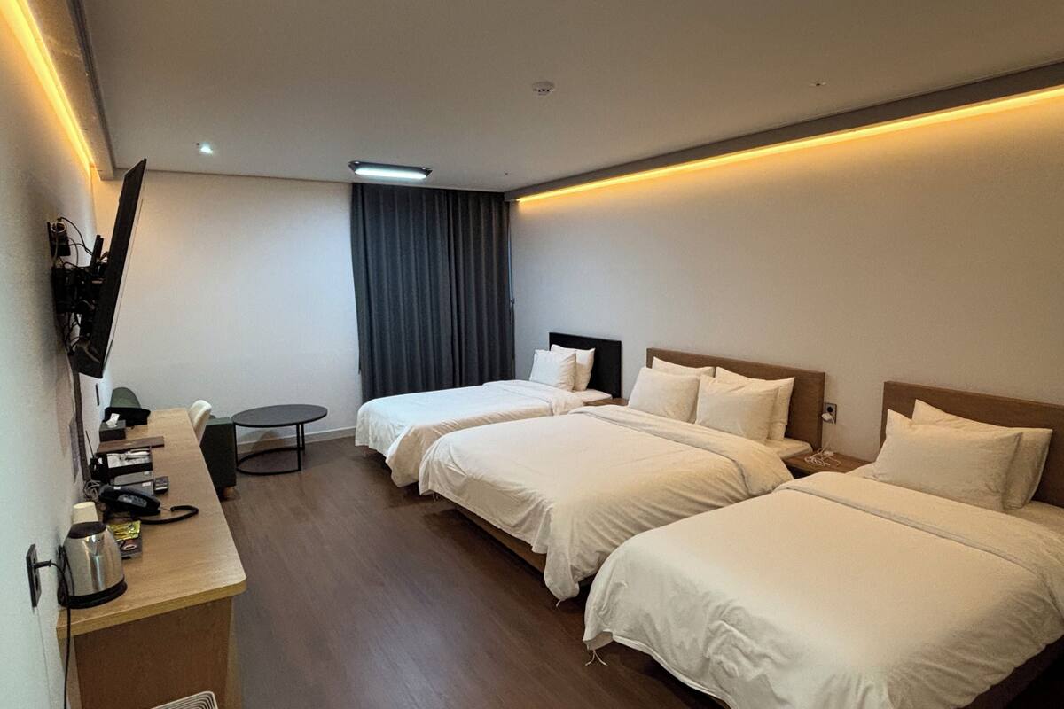 Une chambre d’hôtel avec deux lits, un bureau, une chaise, une petite table et un téléviseur.