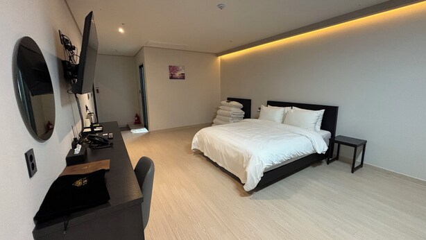 A modern hotel room with a large bed, a desk, and a television. - HOTEL DEOKYEONG (Wonju)