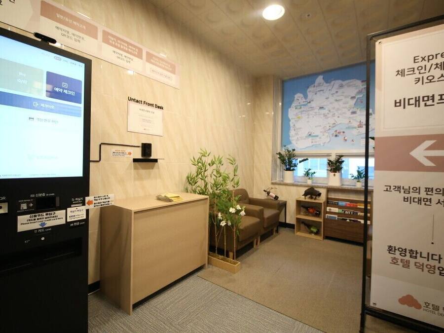 Un área de recepción con una pantalla digital, un mostrador, un mapa en la pared y un cartel con indicaciones.