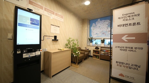 Un área de recepción con una pantalla digital, un mostrador, un mapa en la pared y un cartel con indicaciones.