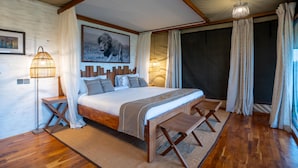 Une chambre à coucher avec un grand lit, une tête de lit en bois et un luminaire fixé au plafond.