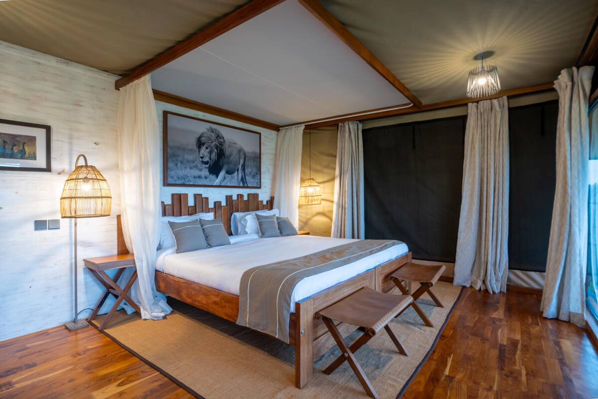 Quarto com cama grande, cabeceira de madeira e luminária no teto.