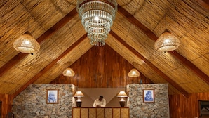 Un intérieur avec un plafond en bois, des murs en pierre, un comptoir d’accueil et deux lampes.