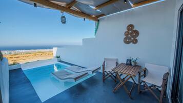 Un espace piscine extérieur moderne avec vue sur l’océan, doté de mobilier en bois et agrémenté d’œuvres d’art murales décoratives.