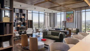A modern living room with a city view, featuring a green sofa, white chairs, and a wooden coffee table. - AC Hotel Santiago de los Caballeros (Santiago de los Caballeros)