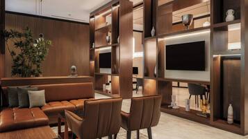 Una sala moderna con un sofá de cuero, una mesa de comedor y sillas, rodeada de estanterías de madera con objetos decorativos y un televisor de pantalla plana.