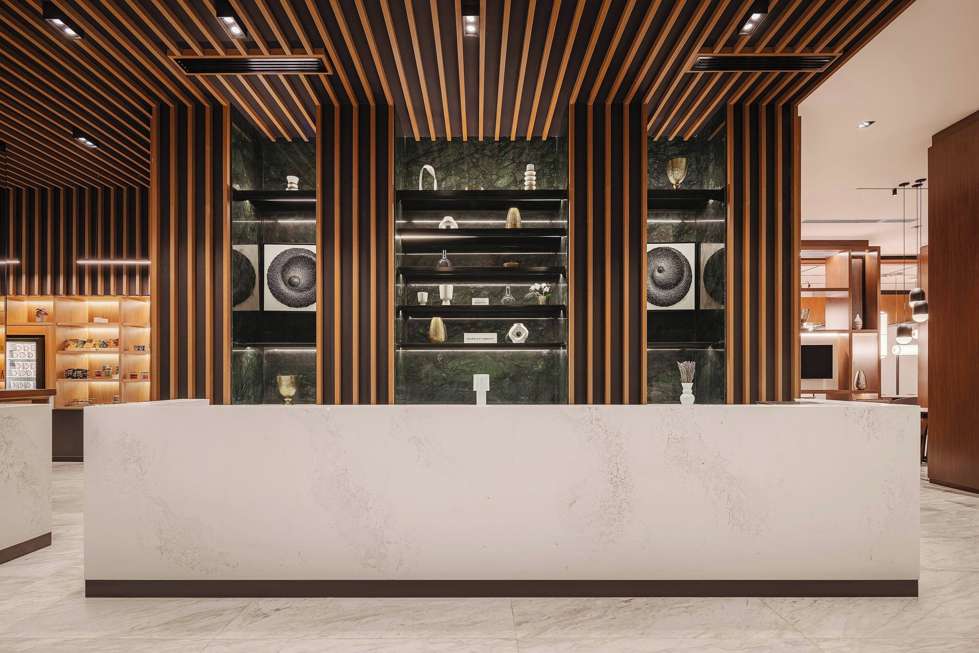 A reception area with a marble counter, wooden paneling, and shelves displaying various items.