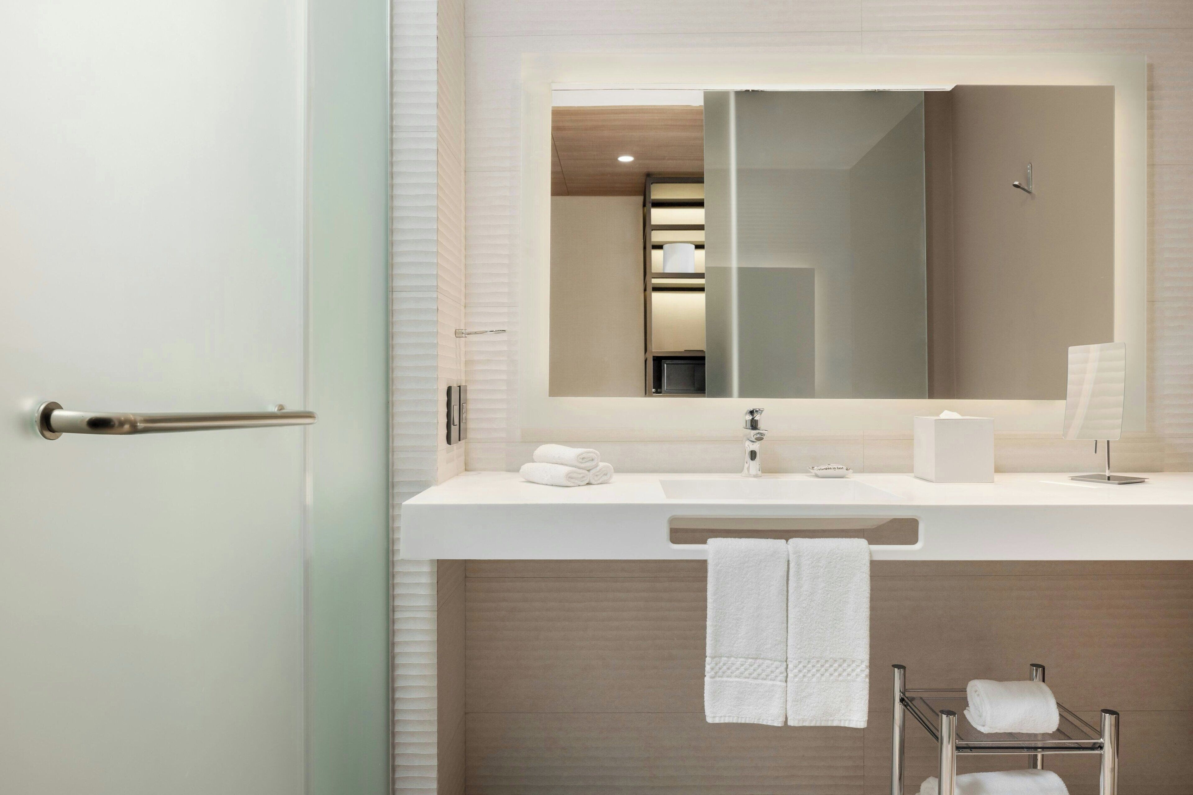Une salle de bain moderne avec un lavabo blanc, un miroir et un porte-serviettes.