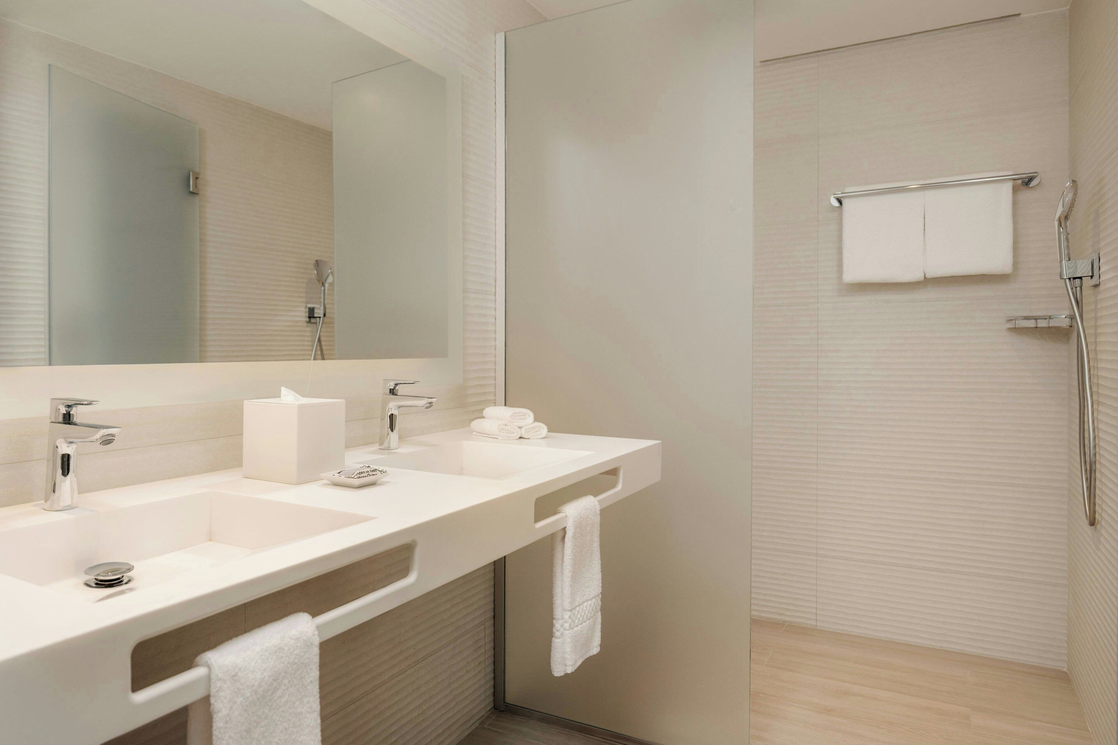 A modern bathroom with a dual sink, a large mirror, and a glass shower enclosure.