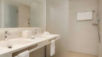 A modern bathroom with a dual sink, a large mirror, and a glass shower enclosure.