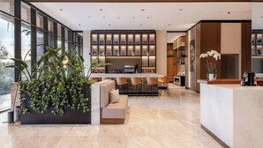 A modern kitchen with a bar area, large windows, and a seating area with a sofa and chairs. - AC Hotel Santiago de los Caballeros (Santiago de los Caballeros)
