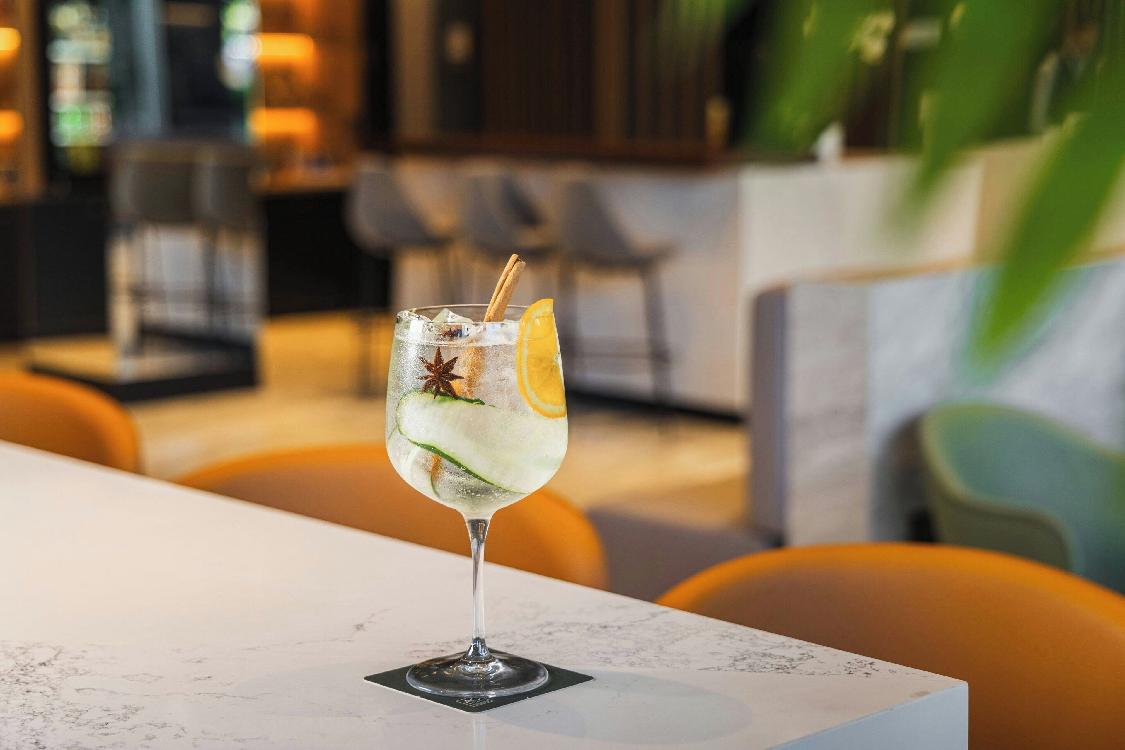 Un verre d’une boisson glacée, garni d’une tranche de citron et d’une étoile de badiane, posé sur une table en marbre dans un restaurant.