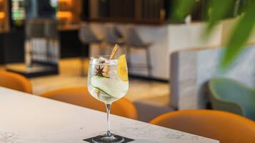 Un verre d’une boisson glacée, garni d’une tranche de citron et d’une étoile de badiane, posé sur une table en marbre dans un restaurant.