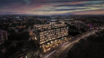 A modern hotel with multiple floors, a well-lit entrance, and a parking area.