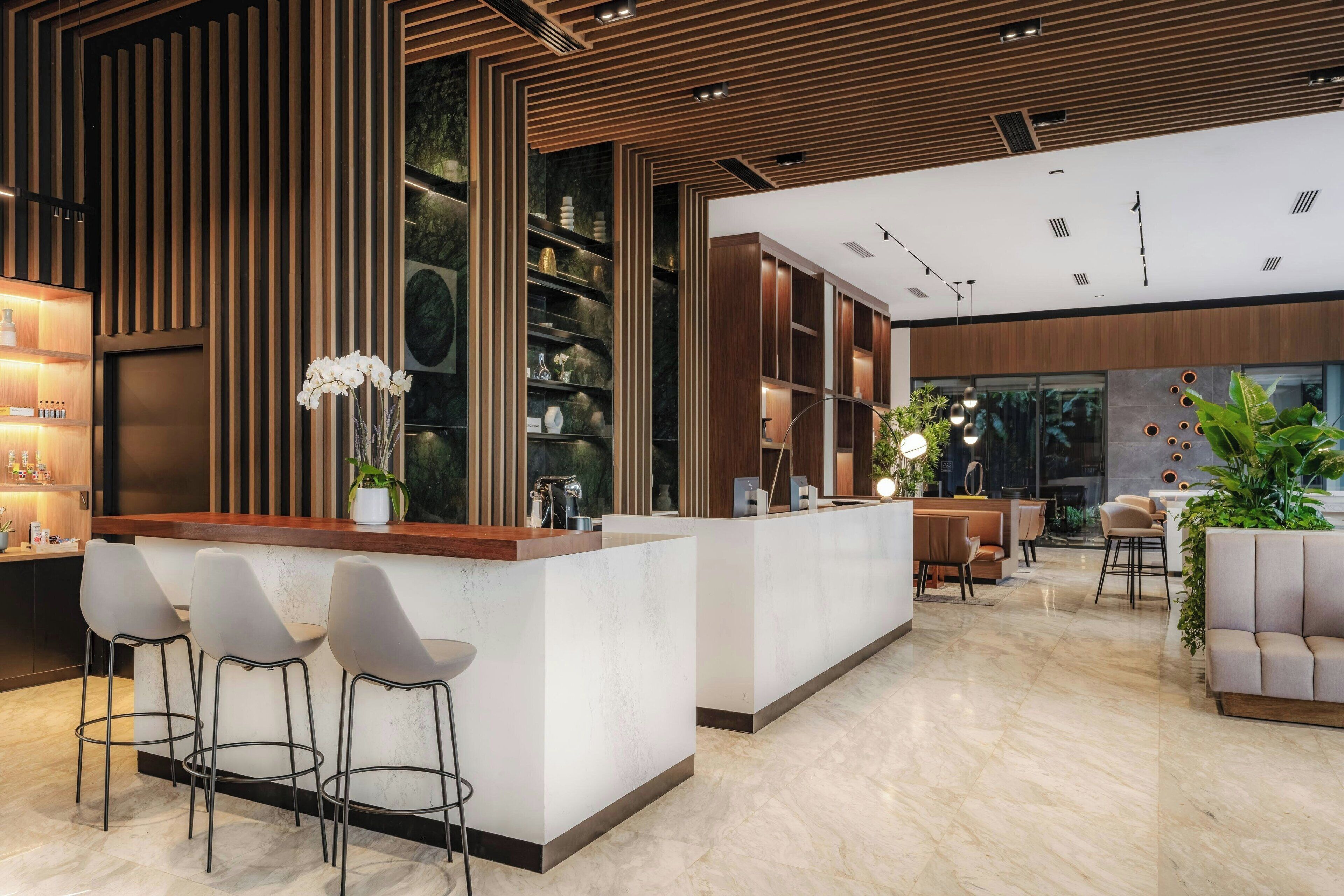 Un interior moderno con una zona de bar central, asientos y un amplio ventanal que proporciona luz natural.