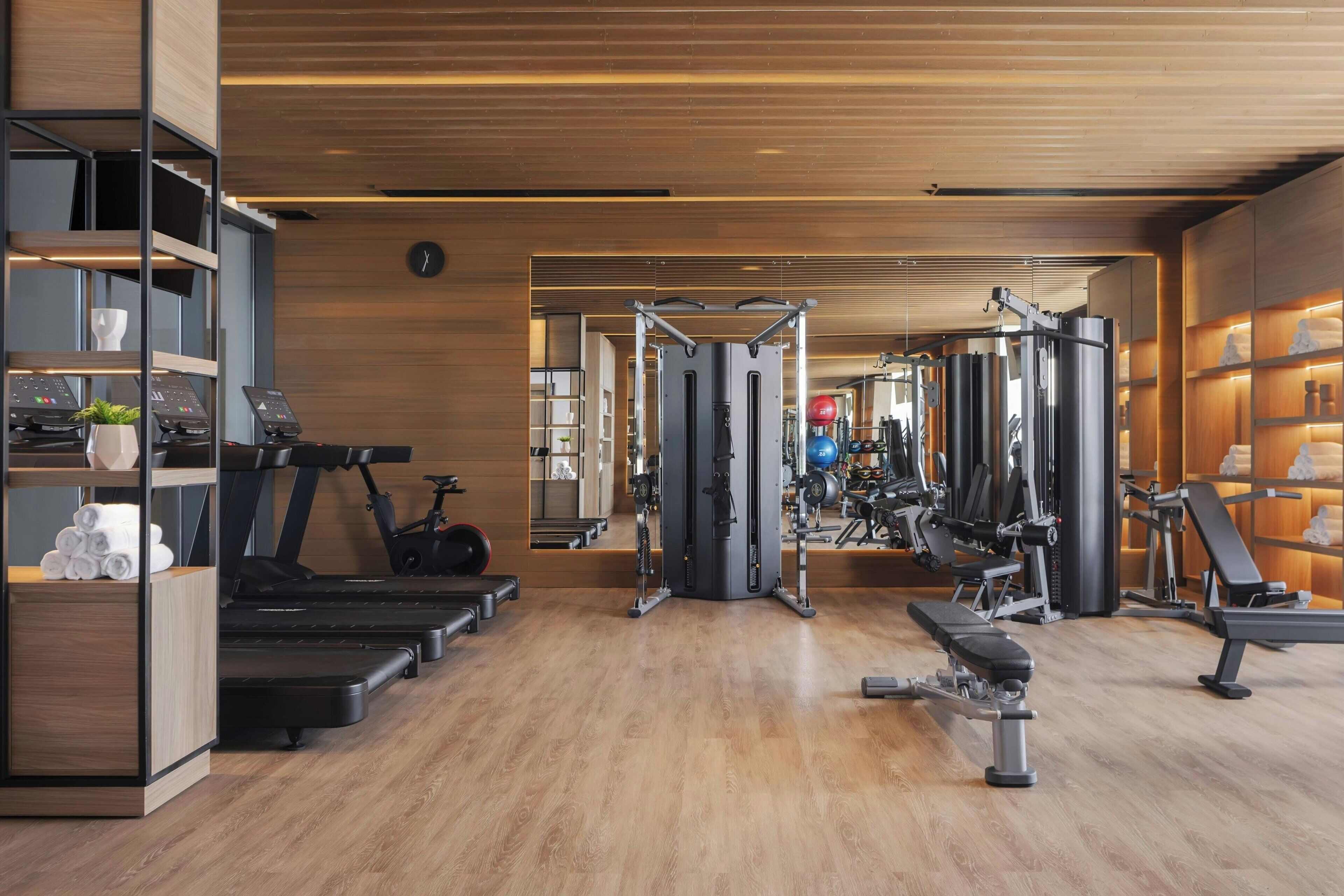 Een moderne sportschool met loopbanden, krachttoestellen en een spiegelwand.