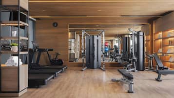 Een moderne sportschool met loopbanden, krachttoestellen en een spiegelwand.