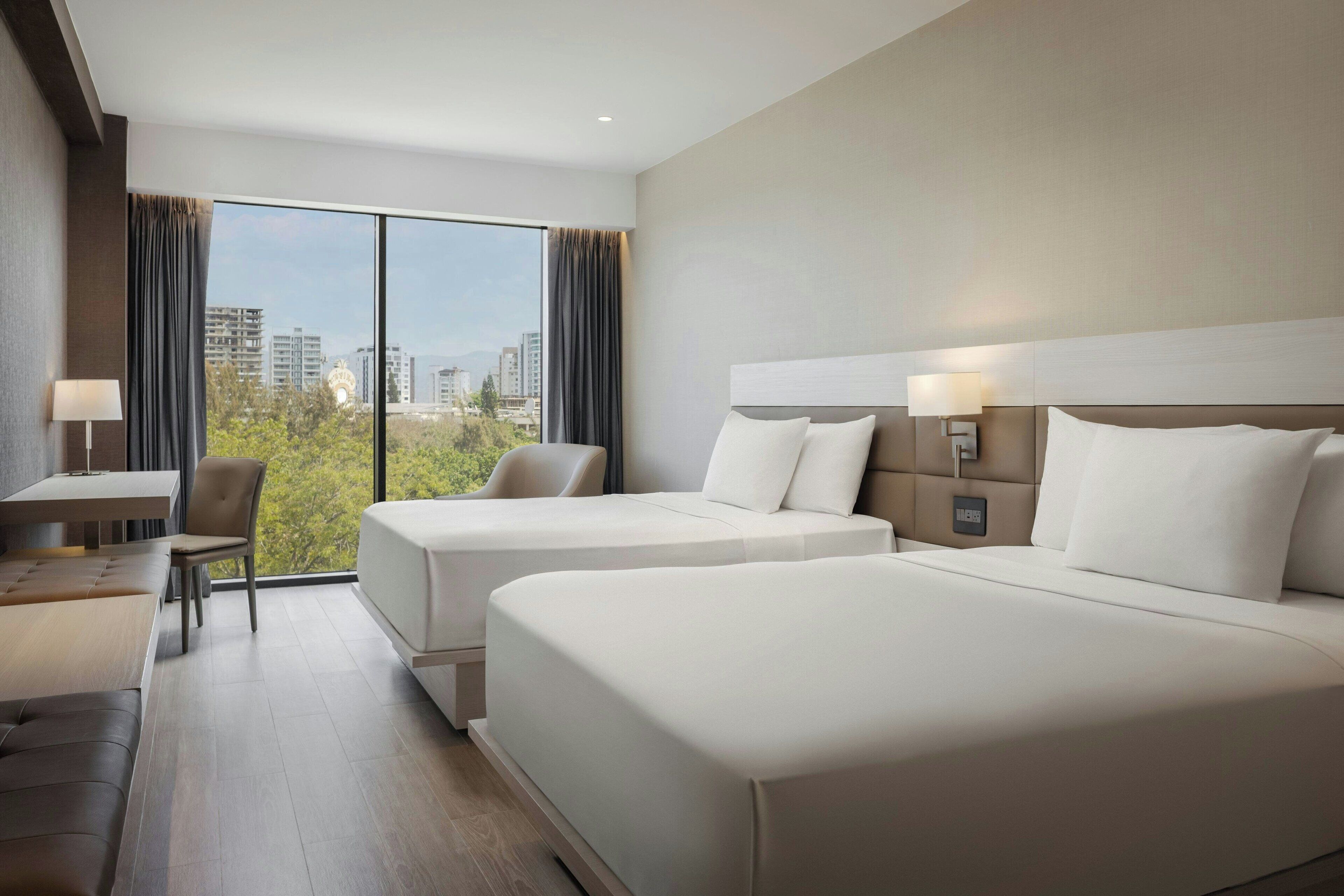 Habitación de hotel con dos camas, un escritorio y una silla.
