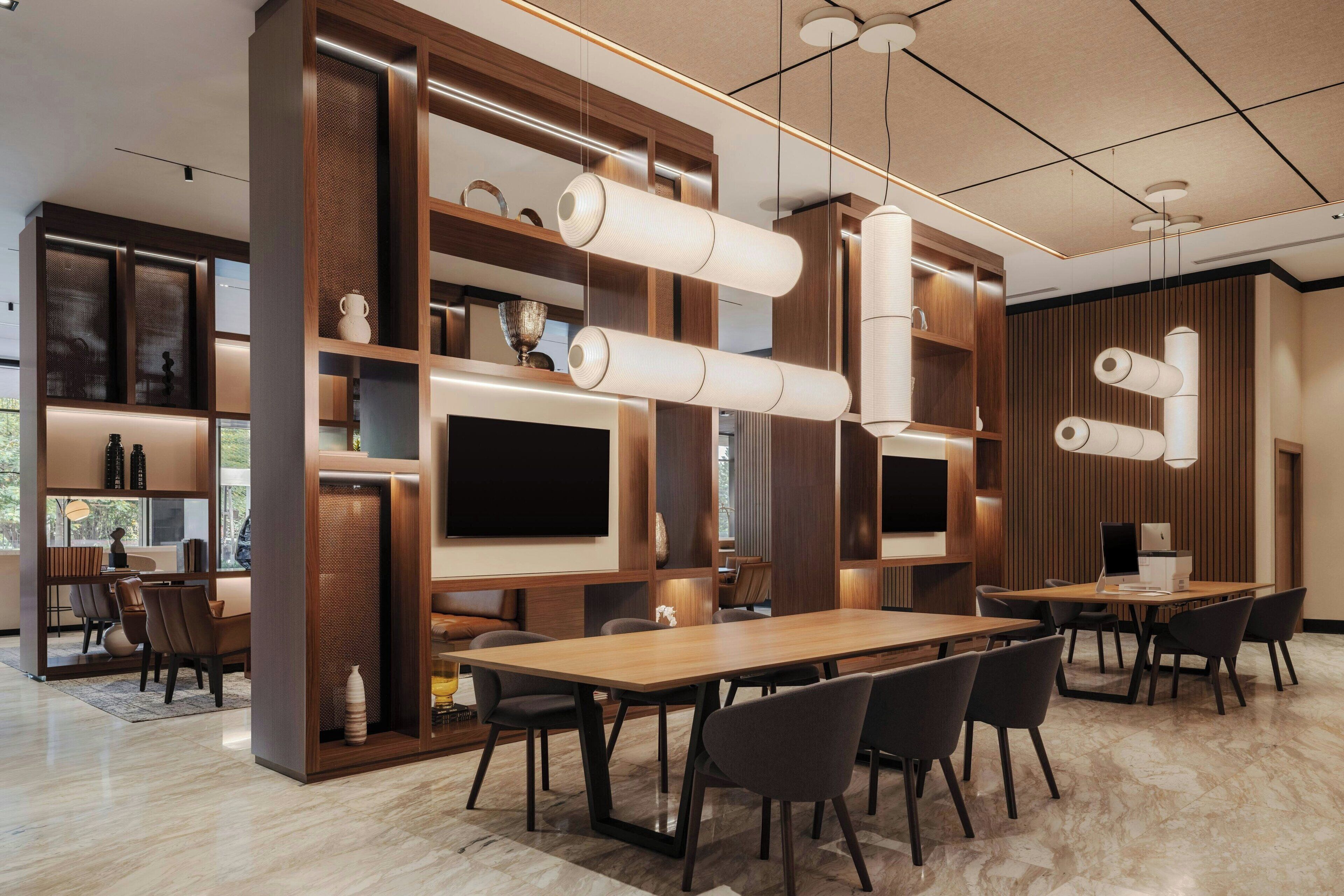 A modern conference room with a long table, chairs, and built-in shelving with decorative items.
