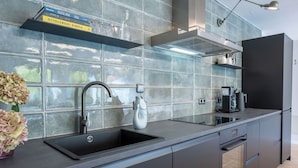 A modern kitchen with a black countertop, stainless steel sink, and built-in oven. - "Designloft Thierhaupten - Creative retreat & Maisonette house " (Thierhaupten)
