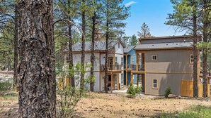 A multi-story building with a mix of residential and commercial spaces, surrounded by trees.