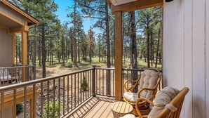 A wooden deck with wicker chairs and a view of a forest.