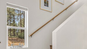 A staircase with wooden steps and a white wall. There are three framed pictures on the wall.