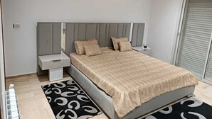 Un dormitorio moderno con cama, mesitas de noche y una alfombra estampada.