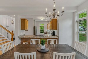 Eine moderne Küche mit Holzschränken, einer Granitabdeckung und einer Kristallleuchtre.