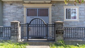 A stone house with a gated entrance, a small window, and a year plaque on the gate. - Lovely ground floor suite in Central Vancouver (Vancouver)