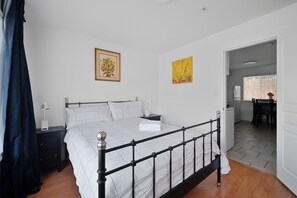 Relax in a serene bedroom with a large bed, bedside table, and framed artworks.
