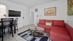 A living room with a red sofa, a glass coffee table, a TV, and a painting on the wall. - Lovely ground floor suite in Central Vancouver (Vancouver)