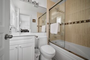 Enjoy a clean and functional bathroom with a bathtub, glass-enclosed shower, and modern sink.