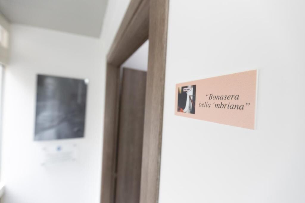 A sign with the text "Bonasera bella 'mbria" on a wall.