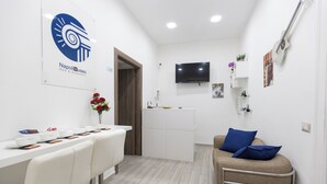A modern hotel room with a dining area, a flat-screen TV, and a bed with blue pillows. - Napoli Museo Bed and Breakfast (Naples)
