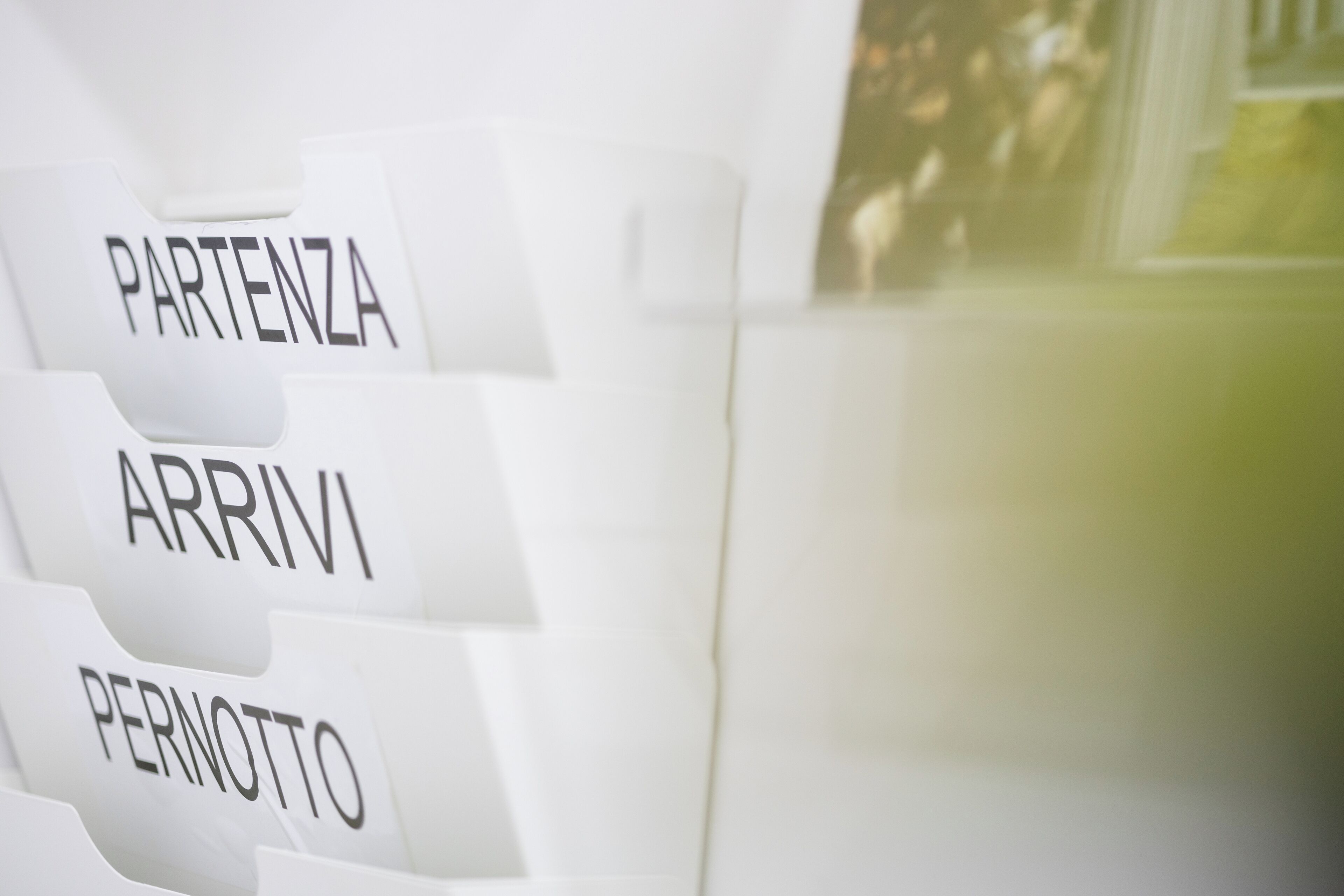 A close-up of a white, segmented piece of furniture with labels reading "PARTENZA," "ARRIVI," and "PERNOTTO."