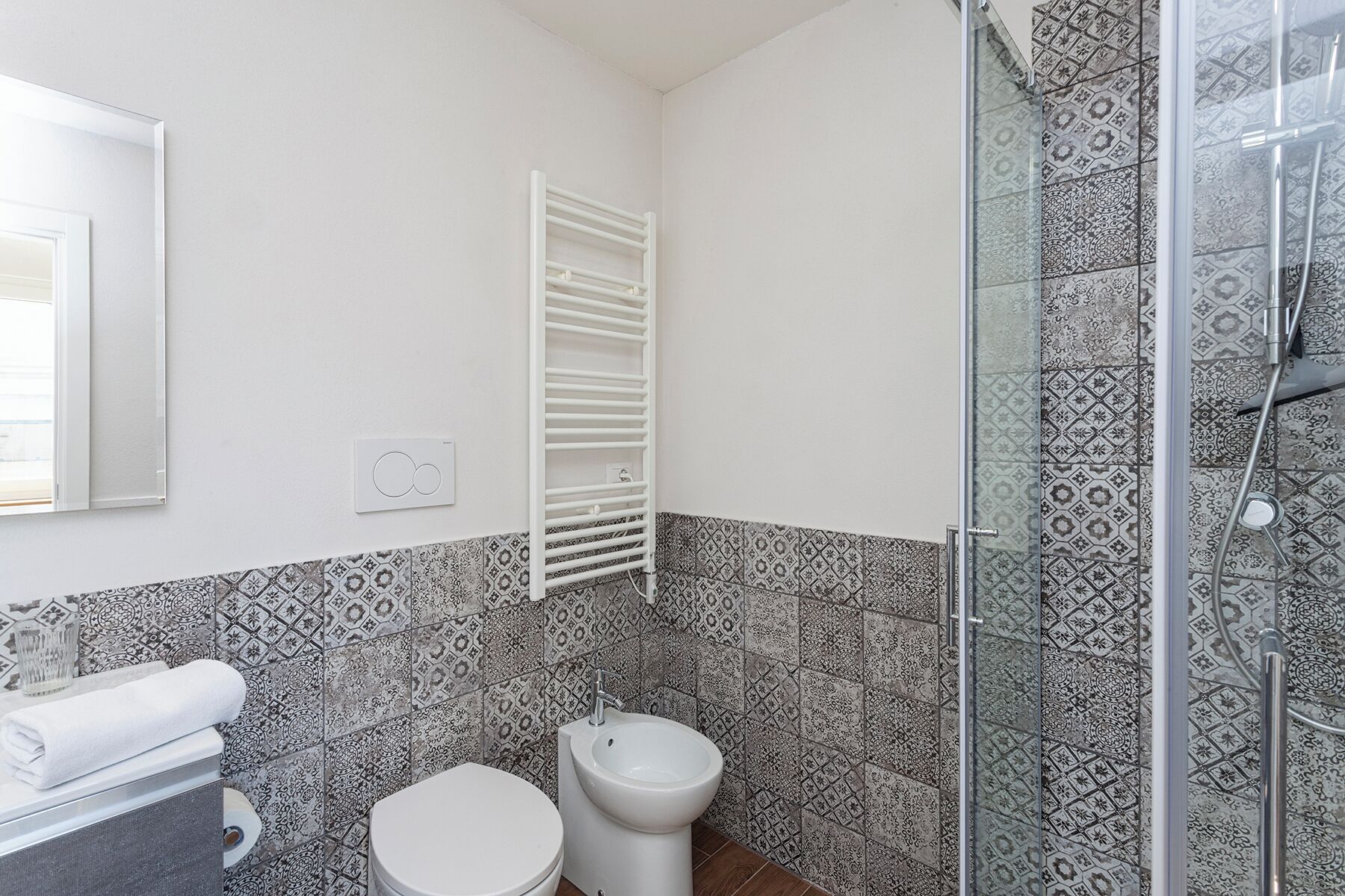 A bathroom with a toilet, bidet, and a glass shower enclosure.
