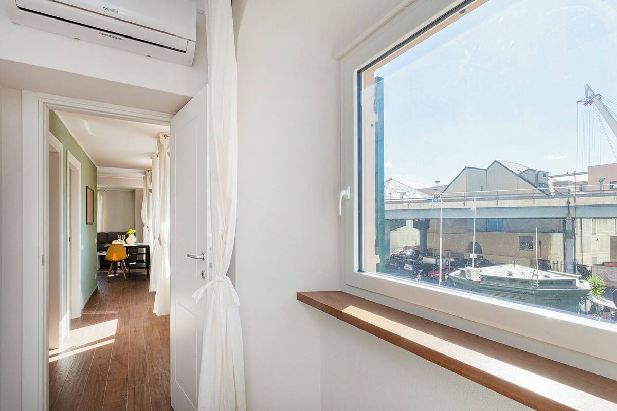 A room with a large window overlooking a construction site, a wooden floor, and a white door.