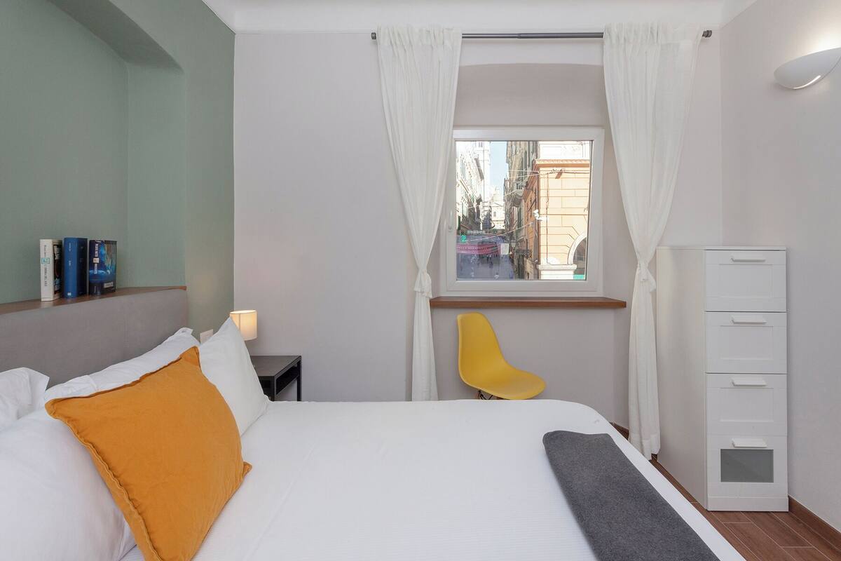 A hotel room with a bed, a chair, a desk, and a wardrobe.